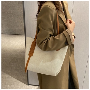 Detail of canvas tote bag with brown leather straps worn on shoulder for commuting