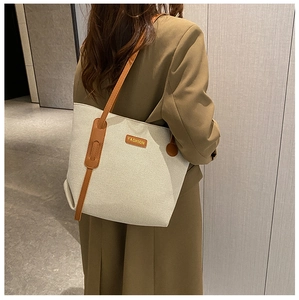 Detailed shot of oversized canvas tote with brown leather straps worn on shoulder