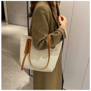 Detail of canvas tote bag with brown leather handles worn with a green blazer