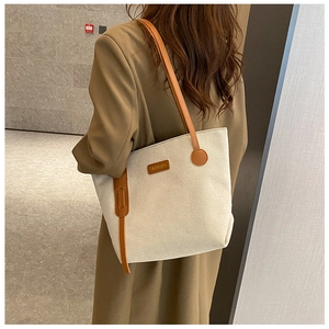 Canvas tote bag with brown leather handles worn by a model in a minimalist modern setting