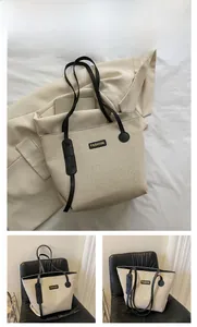 Detail view of large canvas tote bag with black leather straps and fashion label