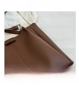 Detailed close-up of dark brown leather texture and silver ring hardware on a tote bag