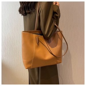 Detailed side view of a large caramel leather tote bag with white stitching on a model