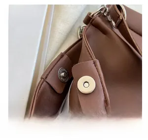 Detail view of strong magnetic closure and silver hardware on a brown shoulder bag