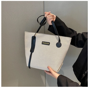 Detail of canvas tote bag showing cream fabric texture and black fashion leather label