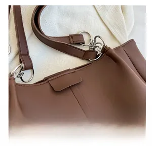 Detail view of reinforced stitching and metal ring attachment on brown leather tote bag
