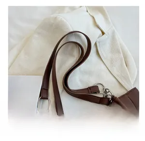 Close-up of a brown tote bag featuring metal rings and decorative chain strap details