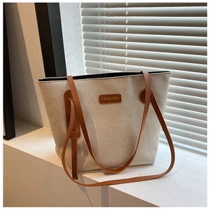 Detail of canvas tote bag featuring premium leather strap and Fashion label on front