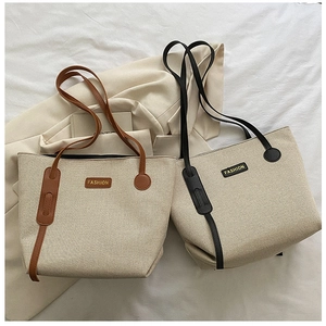 Detail of large canvas tote bag with leather handles and fashion label on soft background