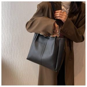Detail of minimalist black leather tote bag with elegant silver ring strap hardware