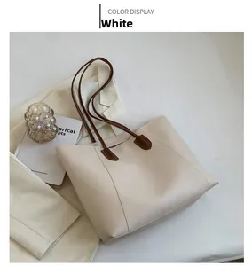 Creamy white tote bag with brown straps styled with a blazer and books in soft light