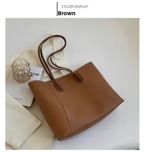 Detail view of brown leather tote bag with white contrast stitching and slim straps
