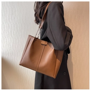 Brown leather tote bag featuring metal chain shoulder straps and stylish vertical stitching