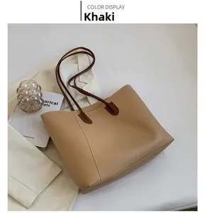 Detail view of khaki large capacity tote bag with dark brown straps in a lifestyle setting