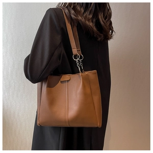 Detail of a brown leather tote bag showing silver metal chain link shoulder strap
