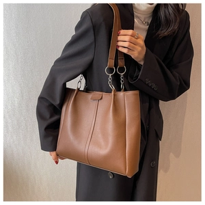 Brown leather tote bag featuring center stitching and metallic chain strap detail