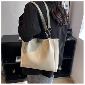Detail of a large off-white tote bag with olive green accents and silver chain strap