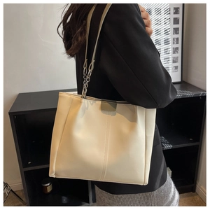 Detail of cream tote bag with vertical stitching and metal chain link shoulder strap