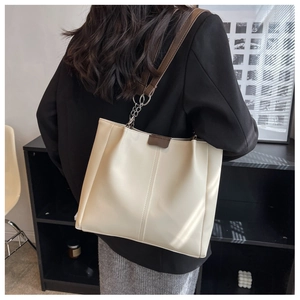 Detail of cream large tote bag showing brown leather straps and silver chain design