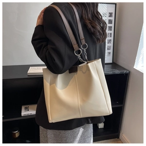 Close-up of cream tote bag with brown straps and silver chain link detail for daily commute