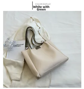 Detail view of large white and green contrast tote bag on white textured background