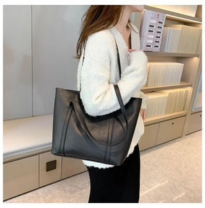 Detail of black leather tote bag with geometric stitching shown in a lifestyle setting