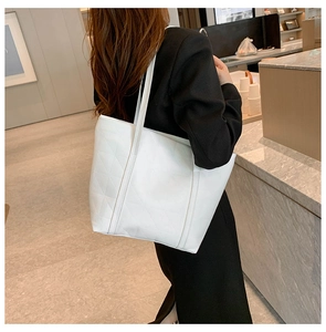 Detailed view of white tote bag with geometric triangle quilting worn by a model