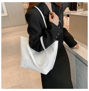Side view of white quilted tote bag with double straps showing capacity on model