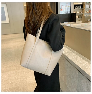 Detailed view of beige tote bag with geometric stitching on a shoulder-carried model