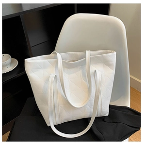 Close-up of geometric quilted texture on white PU leather tote bag with long shoulder strap