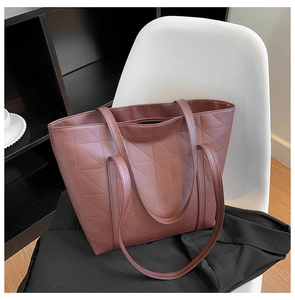 Close-up of geometric quilted patterns on the dark brown leather tote bag on a chair