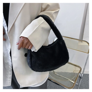 Détail du sac hobo en peluche noire porté par un mannequin dans une tenue d'hiver