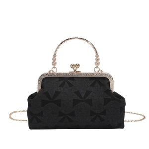 Retro black handbag with bow pattern and golden kiss-lock frame on white background