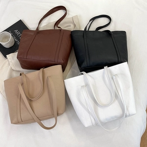 Detailed view of four embossed tote bags in brown, black, beige, and white colors