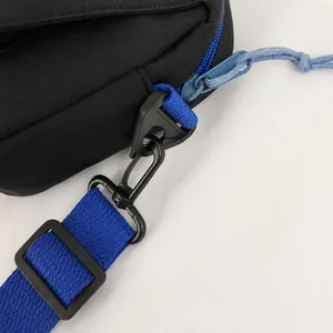 Makro-Detail der schwarzen Umhängetasche mit abnehmbarem blauem Webgurt und Kunststoffhaken