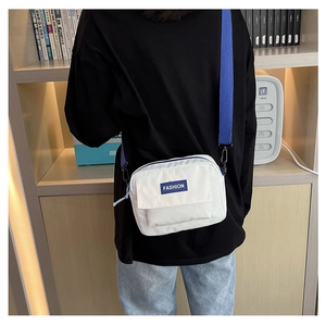 Vista trasera de un bolso bandolera de lona blanca con correa azul y sello FASHION