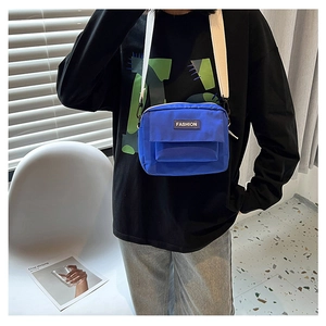 Detalle del bolso bandolera azul Klein con etiqueta de moda y correa blanca ajustable