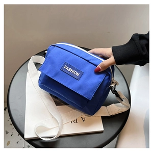 Detalle de bolso bandolera de nailon azul con etiqueta Fashion y correa blanca