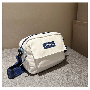 Detalle del bolso bandolera de nailon blanco con etiqueta Fashion y correa azul oscuro
