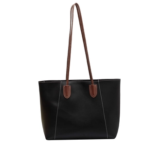 Minimalist black tote bag with brown straps and white contrast stitching detail