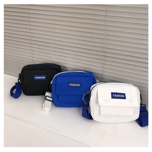 Detalle de bolso bandolera de nailon minimalista con bolsillo de solapa y etiqueta azul