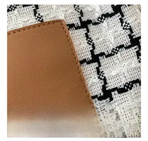 Macro shot of brown lychee leather stitching and black-white checkered wool detail