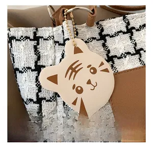 Macro detail of tiger head leather charm on a houndstooth pattern tote bag with gold chain