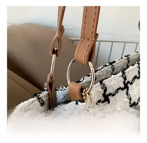Detail of silver rings and heart charm on houndstooth tote bag with brown leather handles