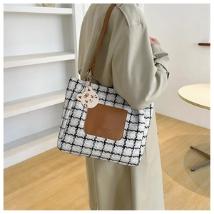 Detail of fashion tote bag featuring houndstooth pattern and leather pocket with logo