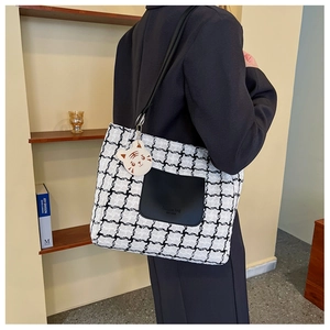 Detail of checkered tote bag with leather pocket and cute tiger bag charm accessory