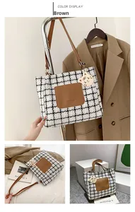 Detail of checkered tote bag featuring a leather pocket and a cute tiger charm attachment