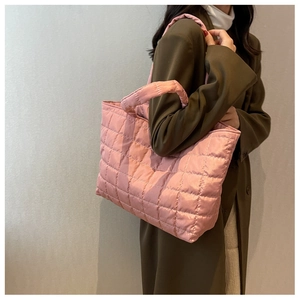 Side view of a large pink quilted tote bag worn with an olive green coat for daily use