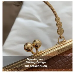 Close-up of golden kiss-lock closure and embossed handle on crocodile pattern bag