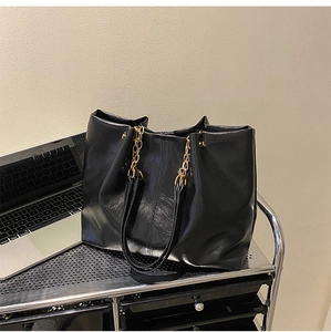 Détail du sac cabas en cuir noir avec bandoulière chaîne dorée et design spacieux